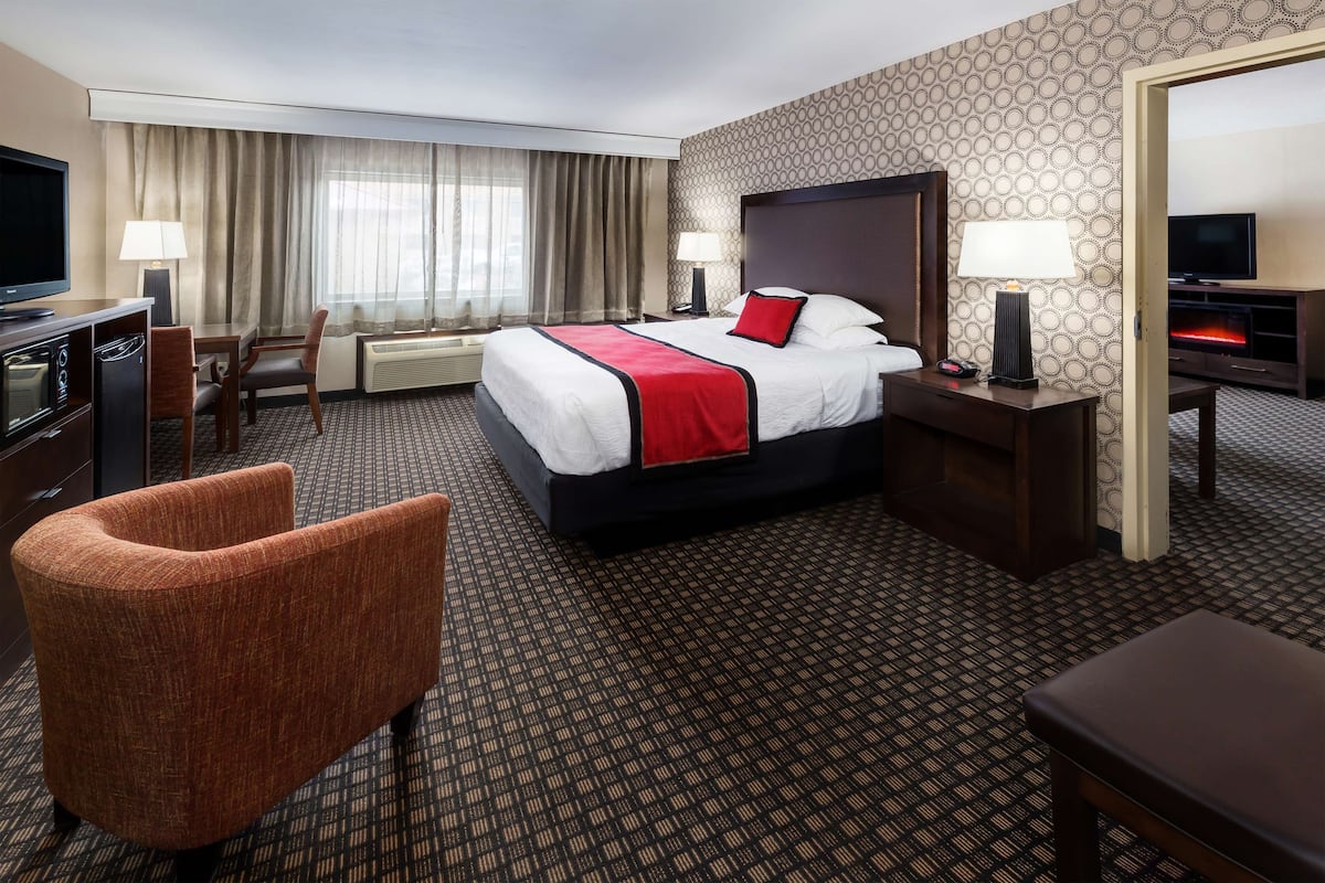 Ein Hotelzimmer mit Bett, Schreibtisch, Stuhl, Fernseher und Kamin.