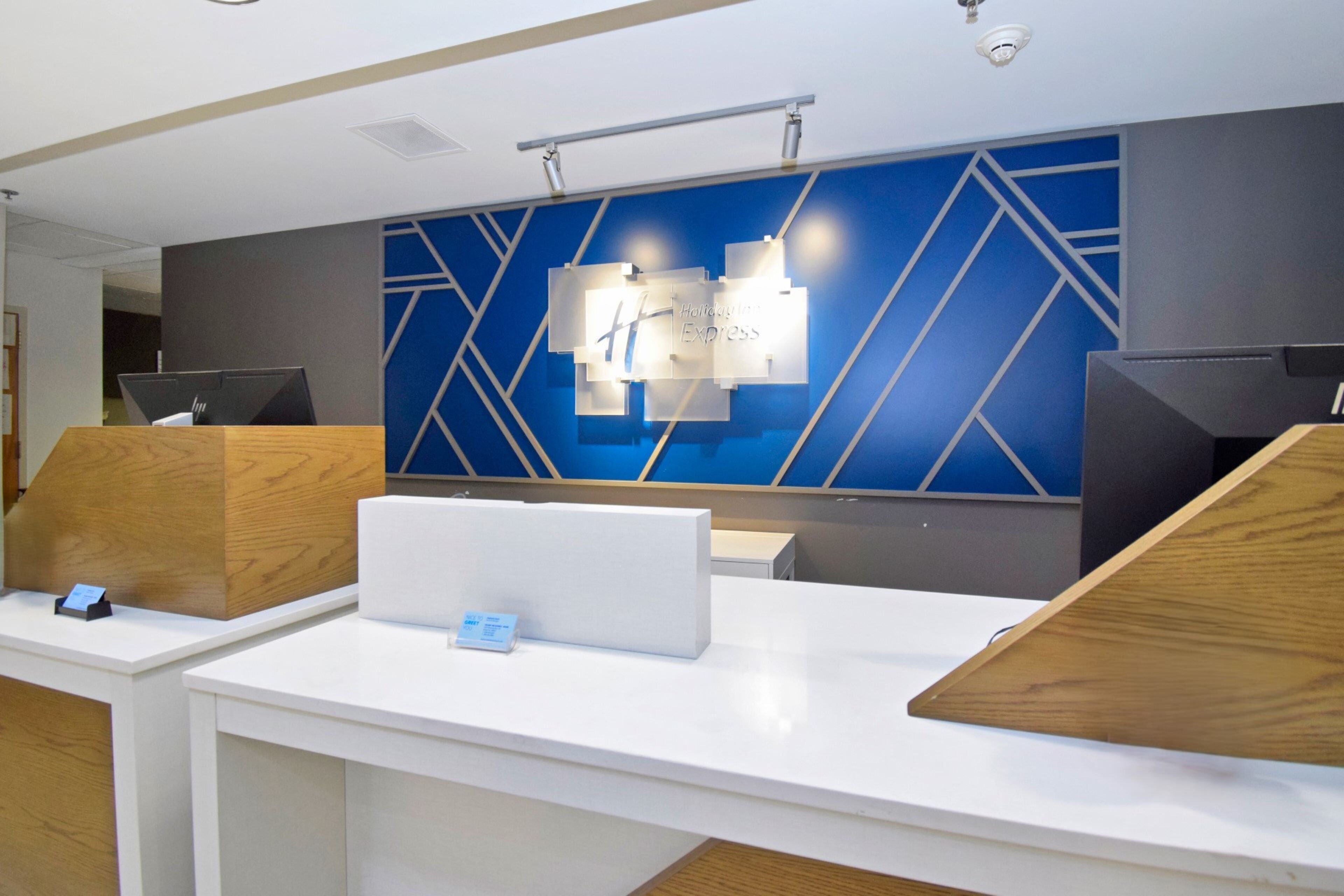 A modern hotel reception desk with a blue geometric wall design and a sign reading "Harvard Express".