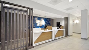 A reception area with a wooden reception desk, a blue accent wall, and a modern ceiling design.