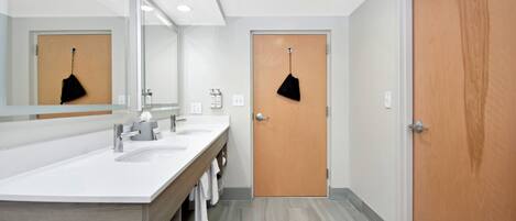 Un baño moderno con un espejo grande, dos lavamanos y una puerta de madera.
