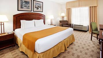 Una camera d'hotel con un letto grande, due lampade ai comodini, una sedia, un condizionatore d'aria e due quadri appesi al muro.