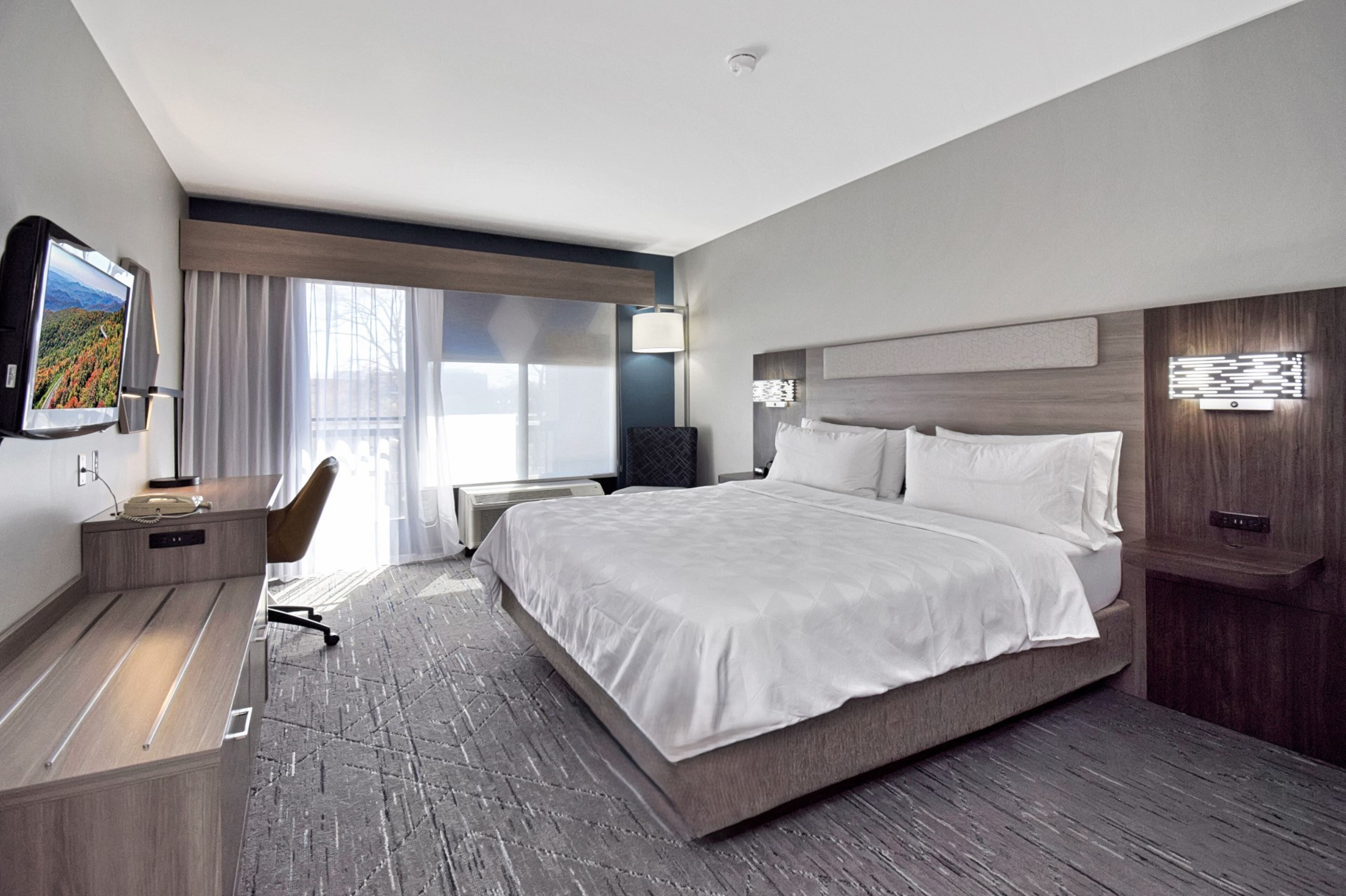 Une chambre d’hôtel moderne équipée d’un grand lit, d’un bureau, d’une chaise et d’un téléviseur.