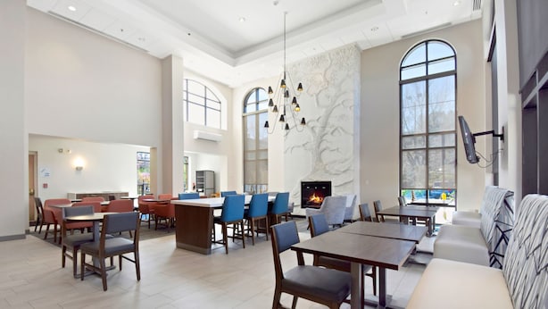A spacious dining area with high ceilings, large windows, and a fireplace.