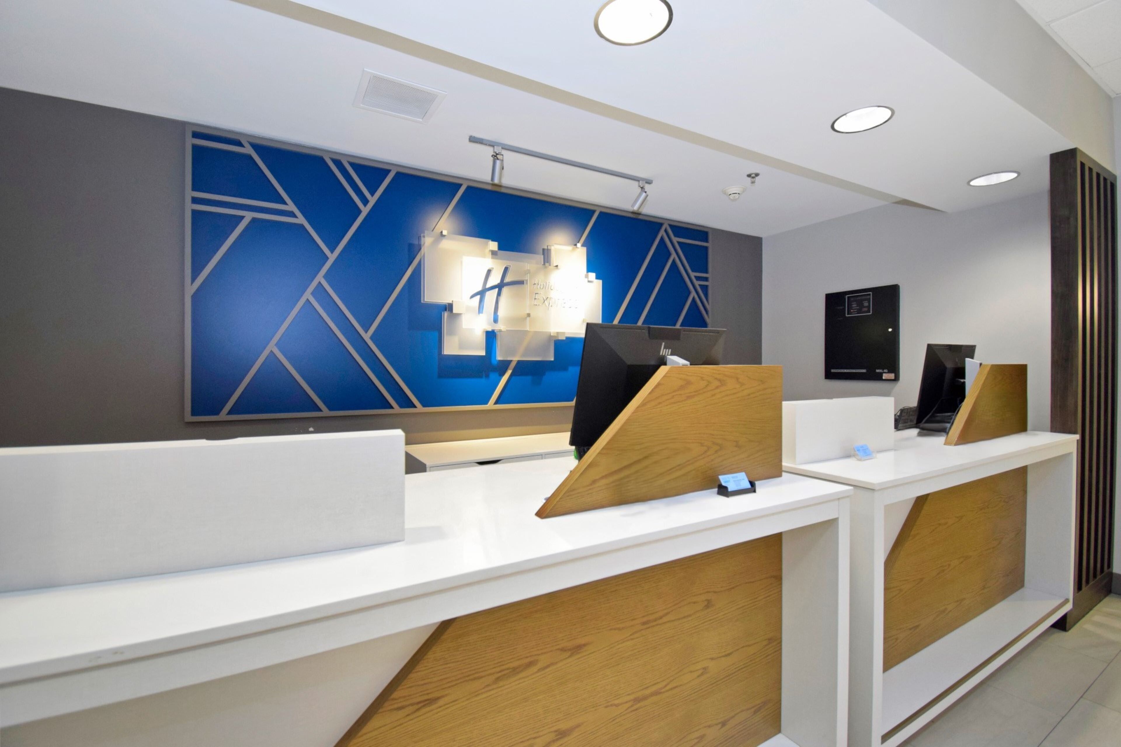 A modern reception desk with a blue geometric wall design, a white countertop, and wooden accents.