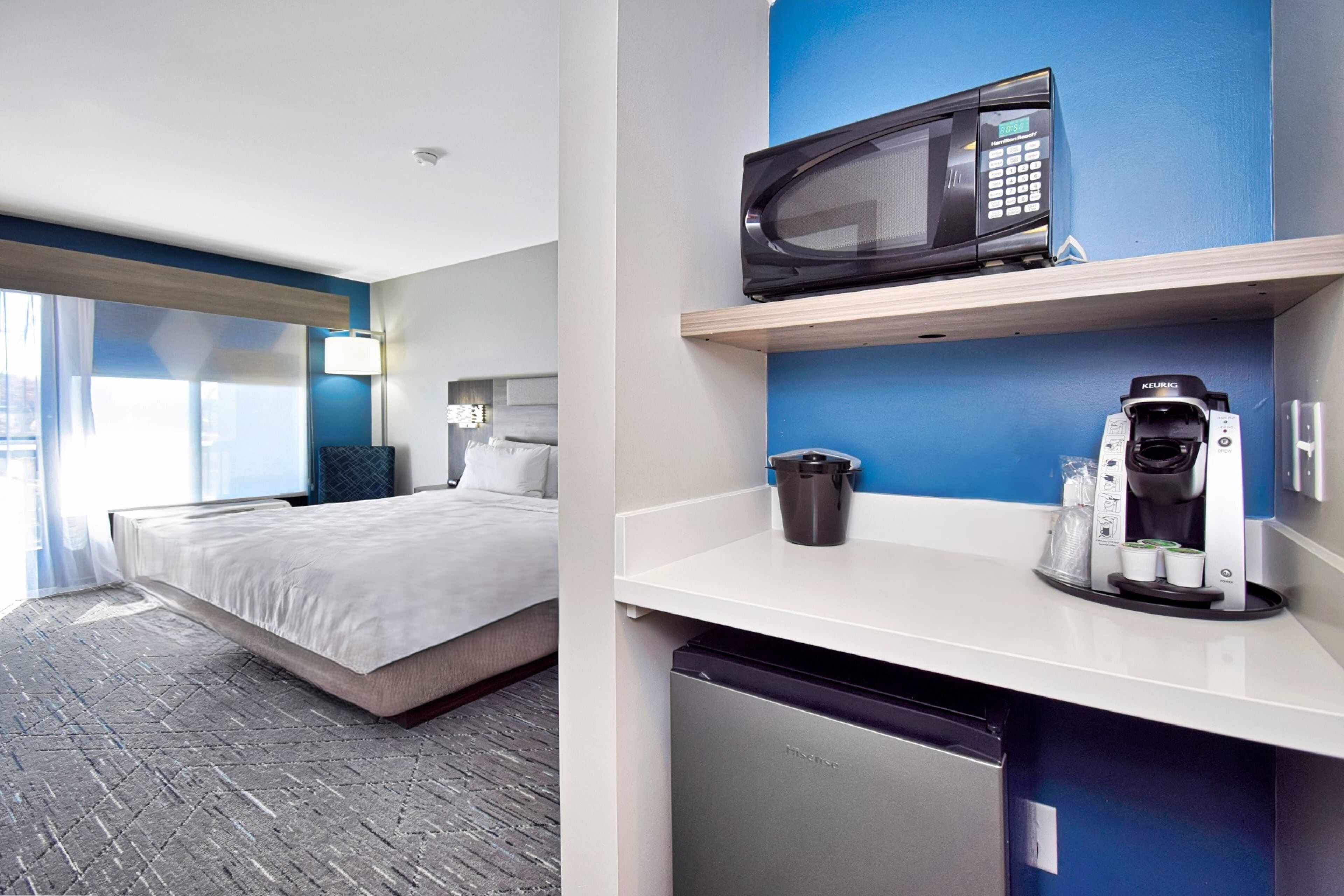 Une chambre d’hôtel équipée d’un lit, d’un four à micro-ondes, d’une machine à café et d’un petit réfrigérateur.