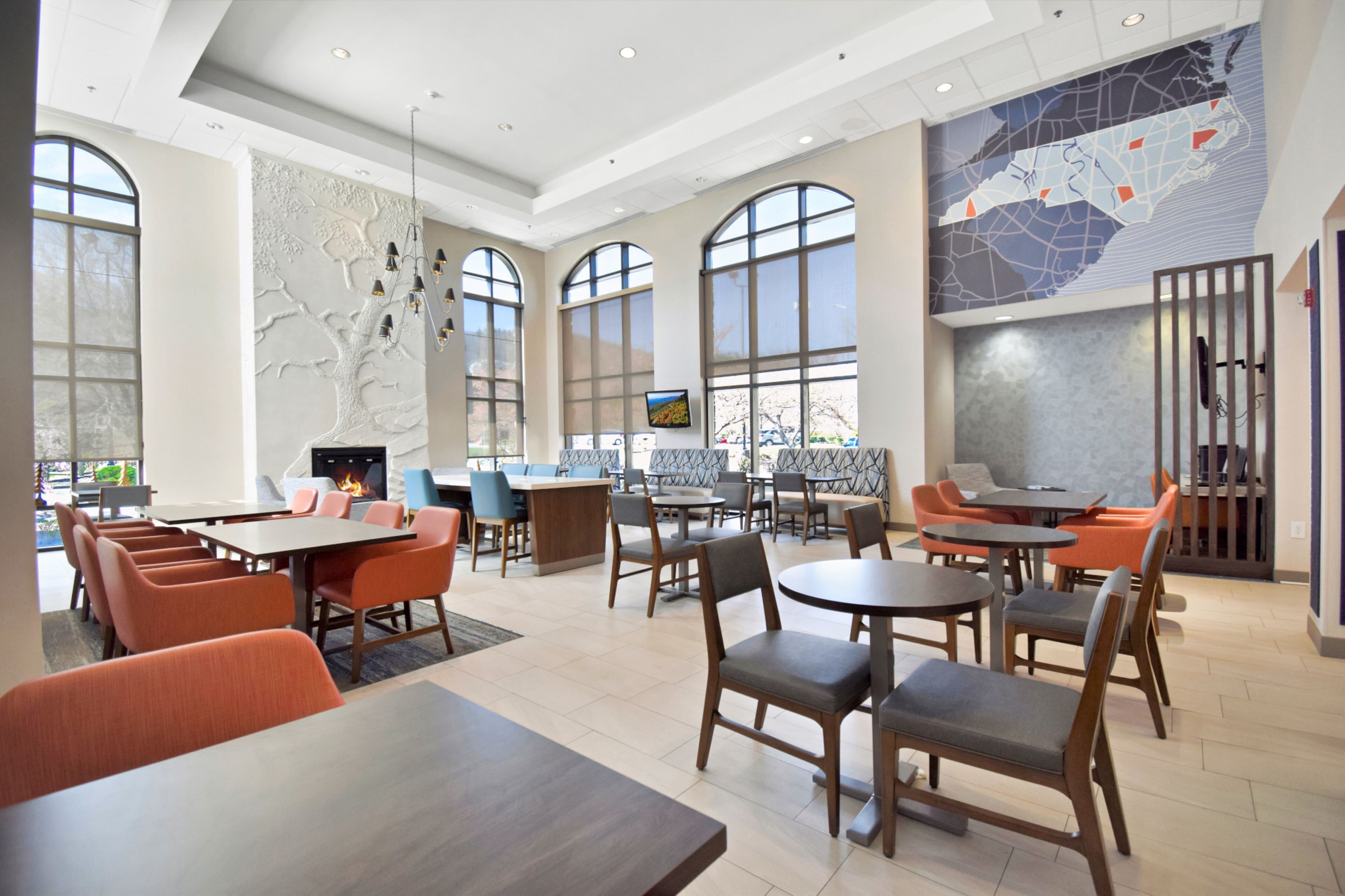A spacious indoor area with multiple seating arrangements, including tables and chairs, and a fireplace.
