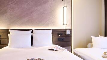 A hotel room with a large bed, a bedside table, a wall-mounted light, and a power outlet.
