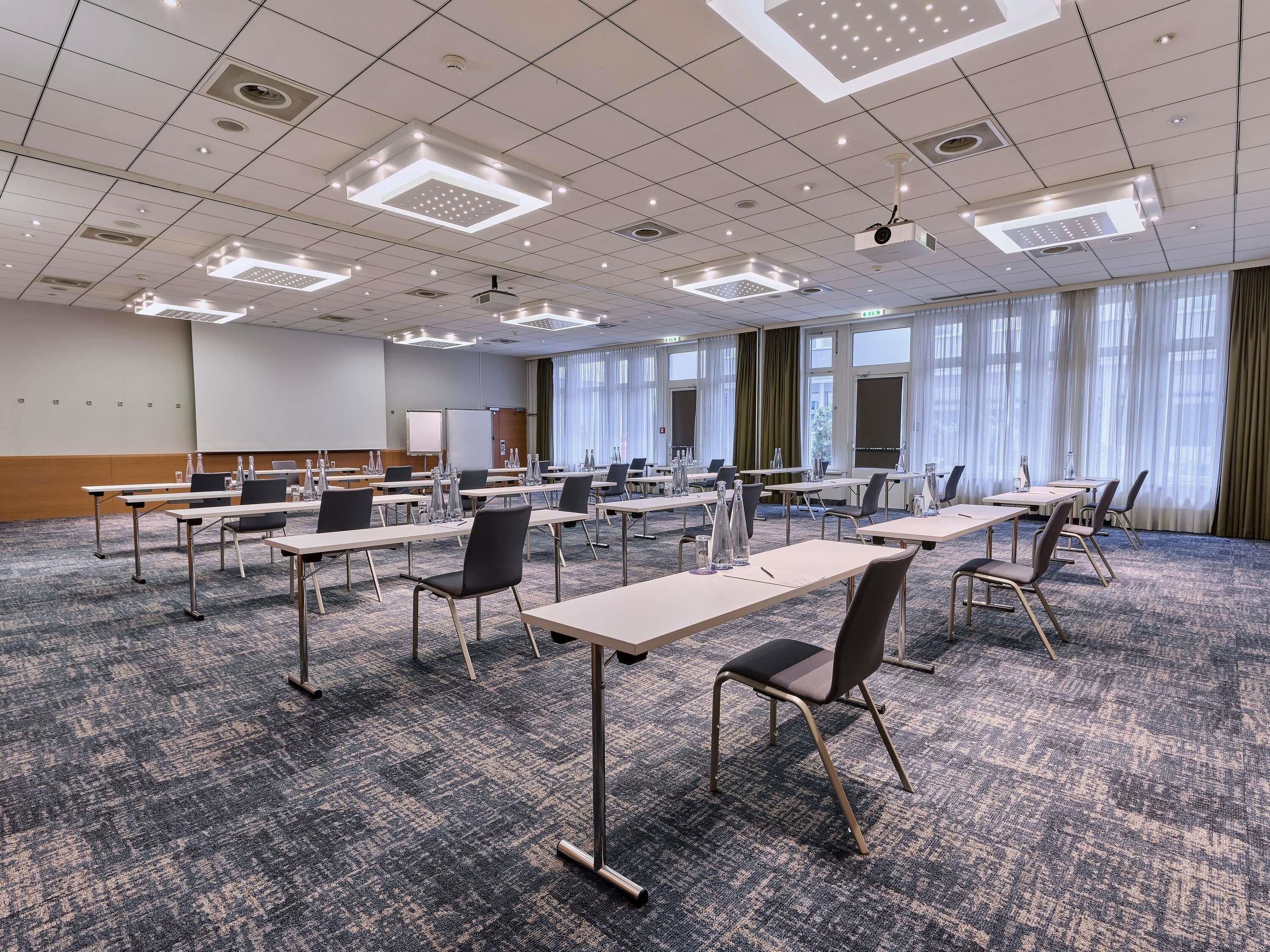 A conference room with tables, chairs, a projector, and a whiteboard.