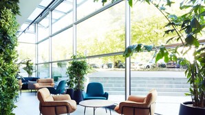 Un interior moderno con ventanas amplias, plantas de interior y zonas de estar.