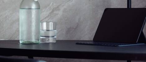 Ein Laptop auf einem Tisch, neben ihm eine schlichte Glasflasche und ein kleiner Behälter.
