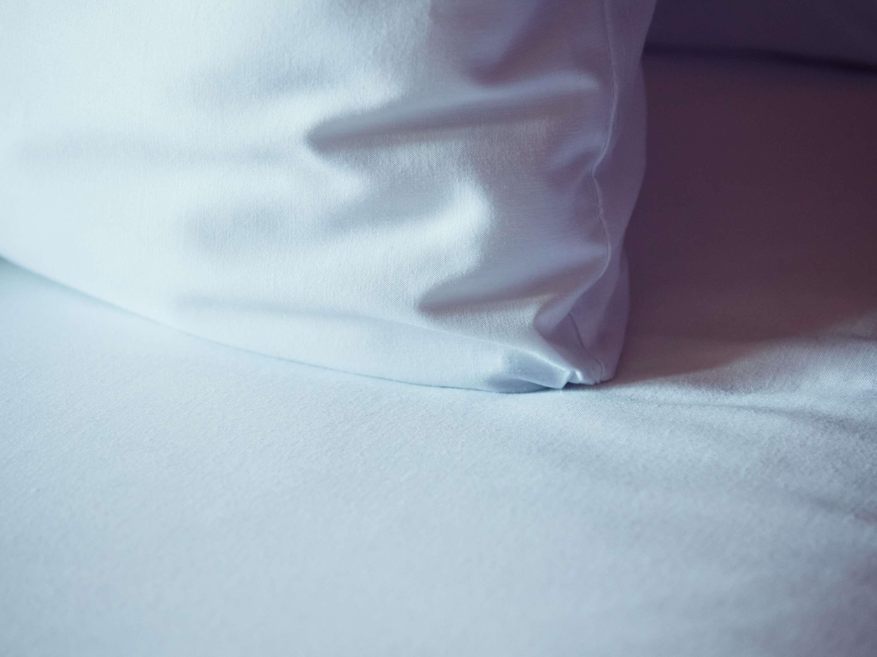 A close-up of a white pillow on a bed.