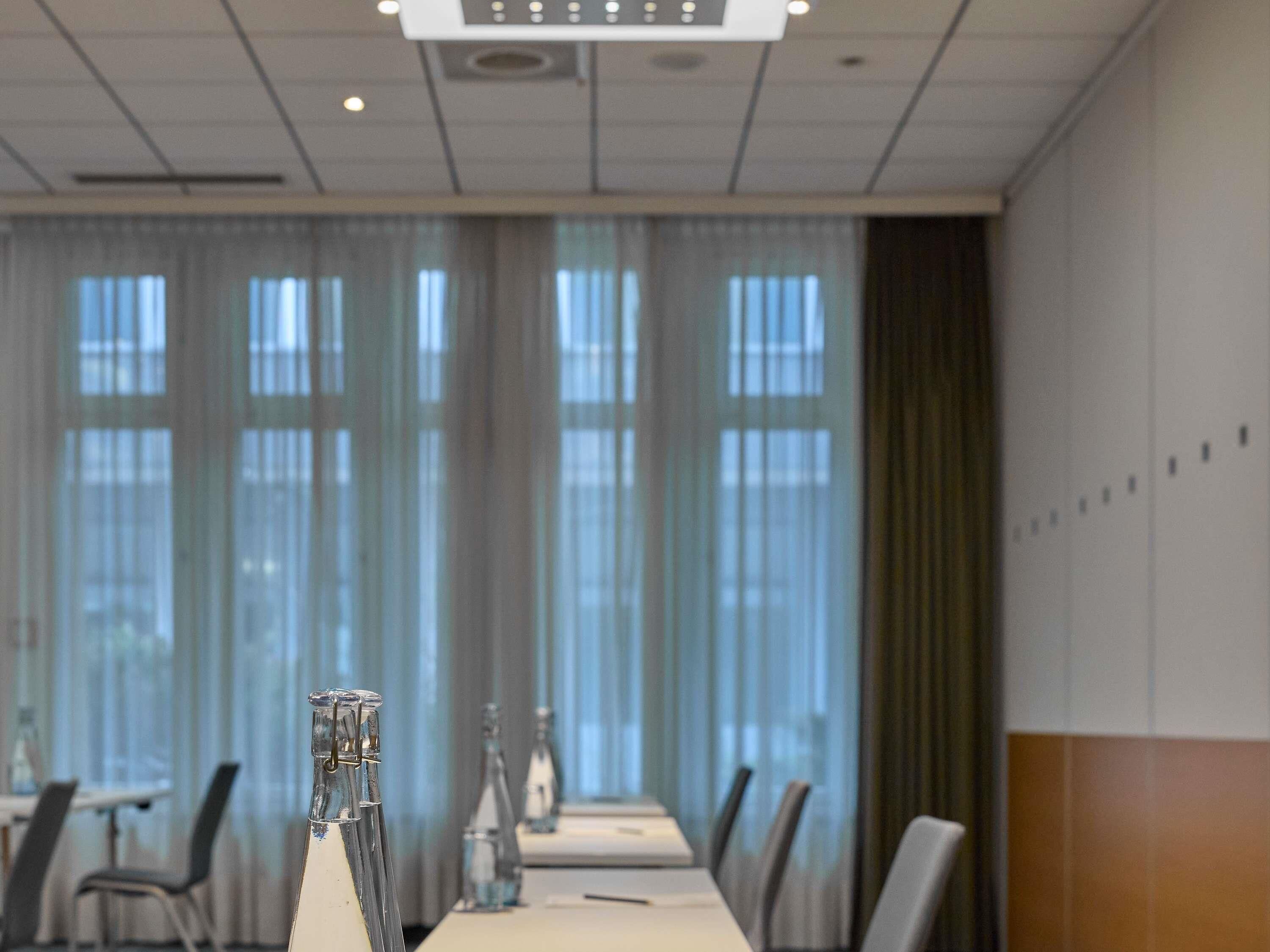 A conference room with a long table, chairs, and a bottle of water.