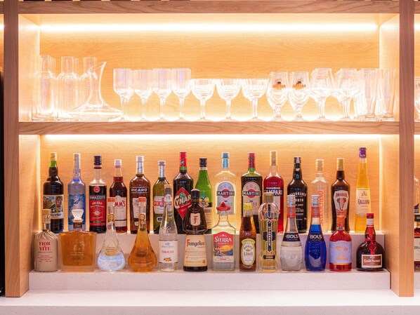 A bar area with multiple bottles of liquor and a selection of wine glasses.