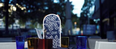 A table set with plates, glasses, and a menu stand with a leaf pattern.