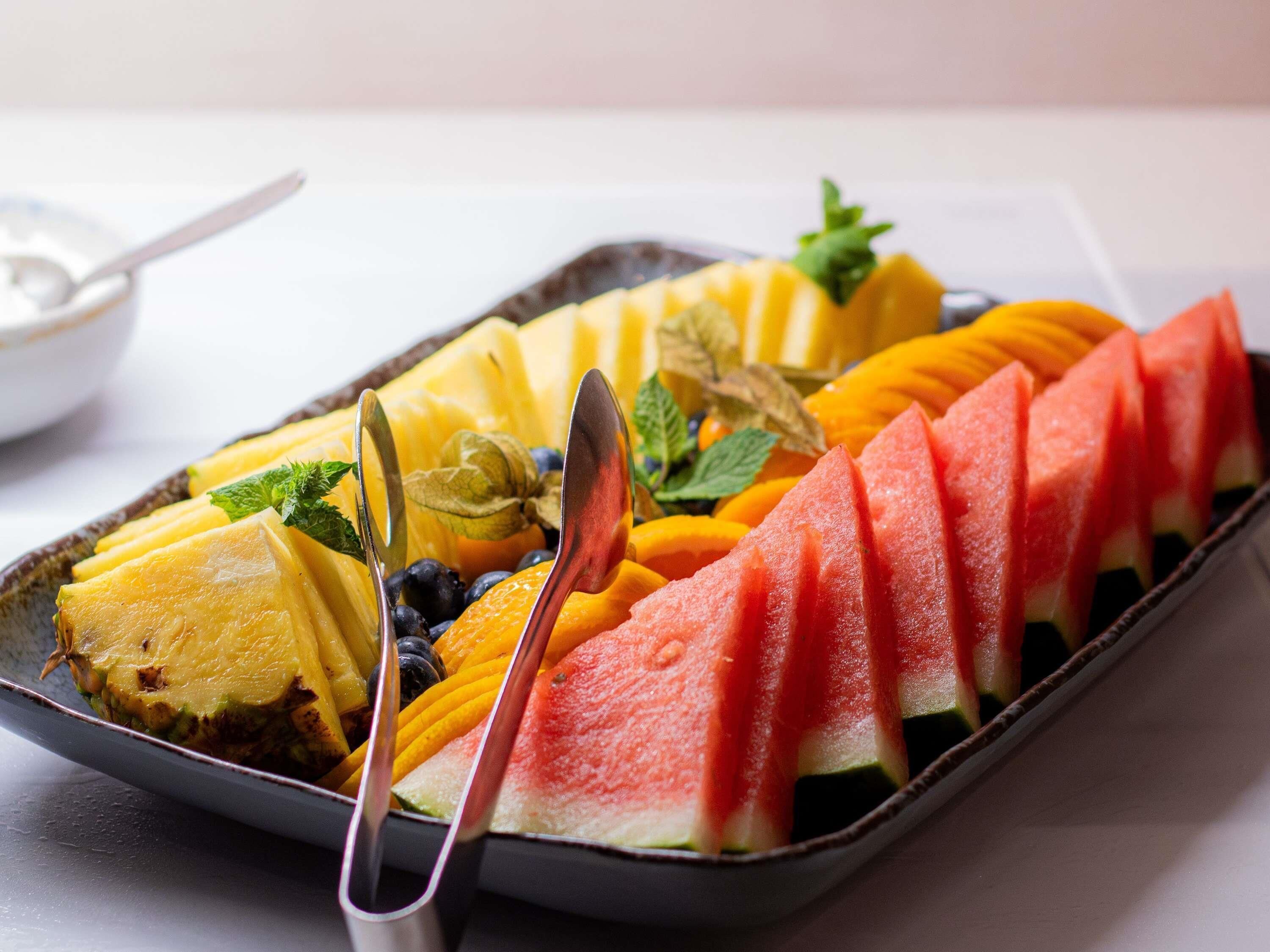 A tray of sliced fruits including watermelon, pineapple, mango, and blueberries.