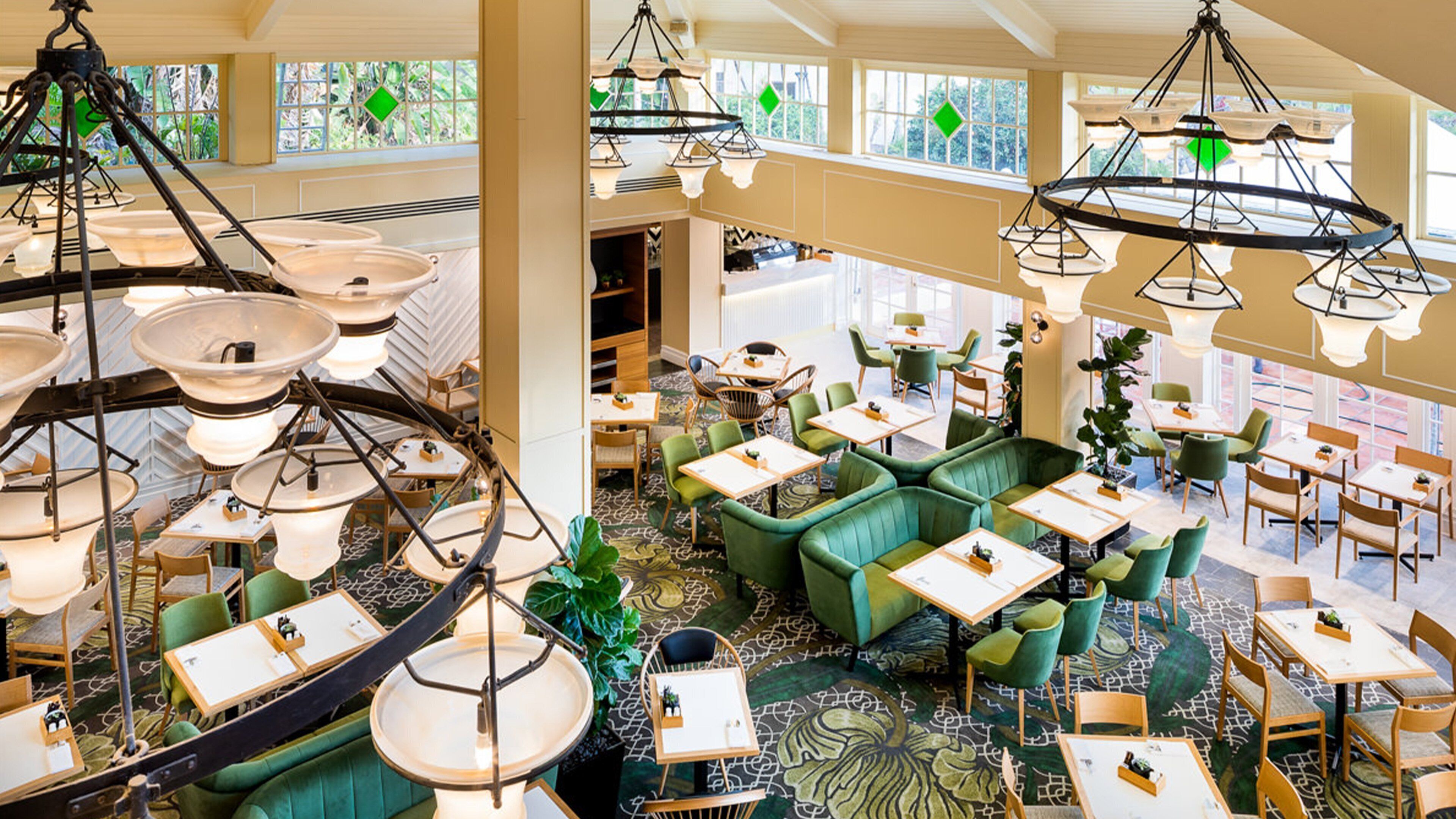 A spacious indoor area with multiple tables and chairs, large hanging light fixtures, and a patterned carpet.