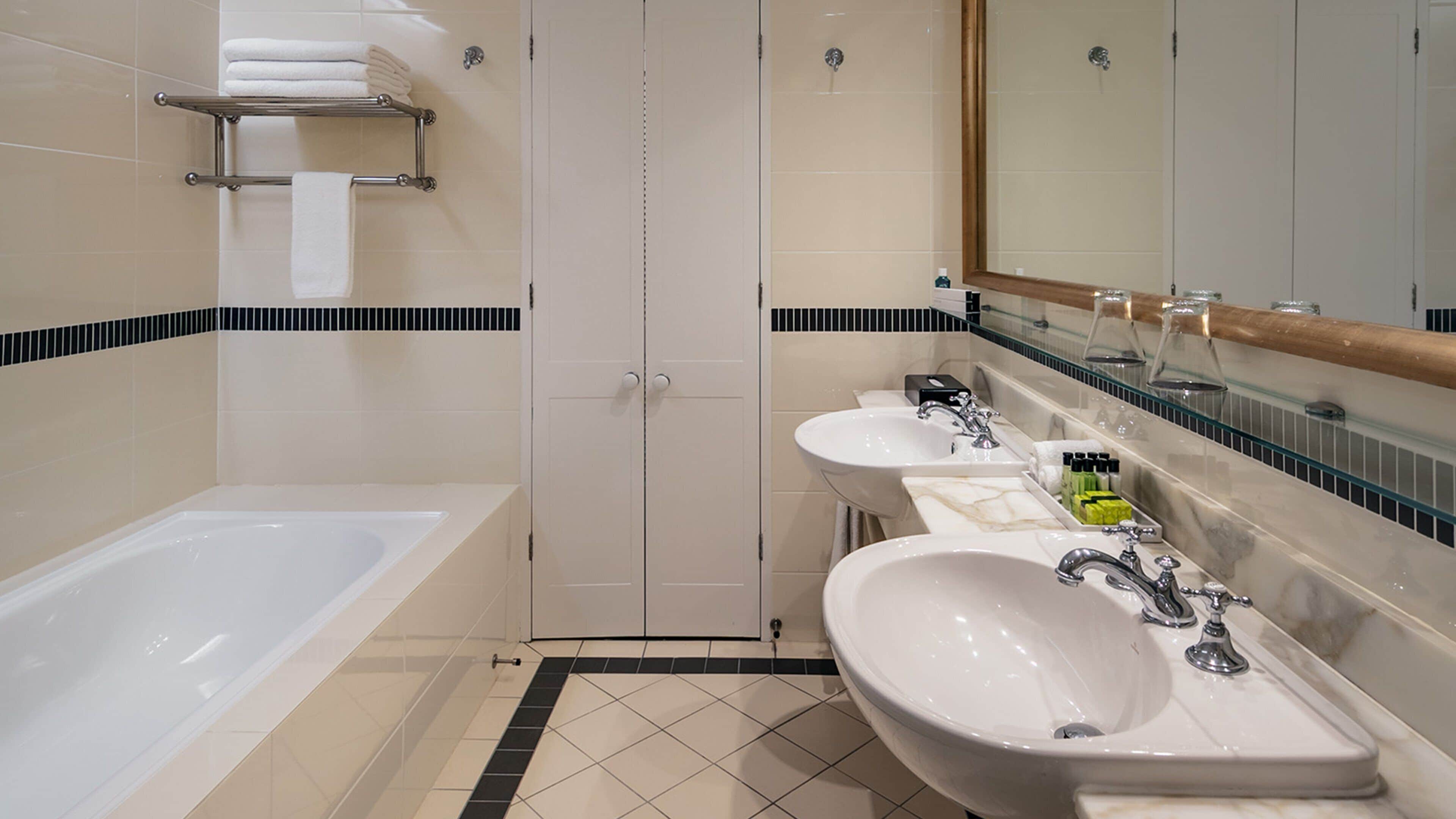 Une salle de bain moderne avec une baignoire, trois lavabos et un grand miroir.