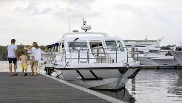 Una familia sube a un barco blanco con un dispositivo Garmin en la parte superior, amarrado en un puerto deportivo con otros barcos.