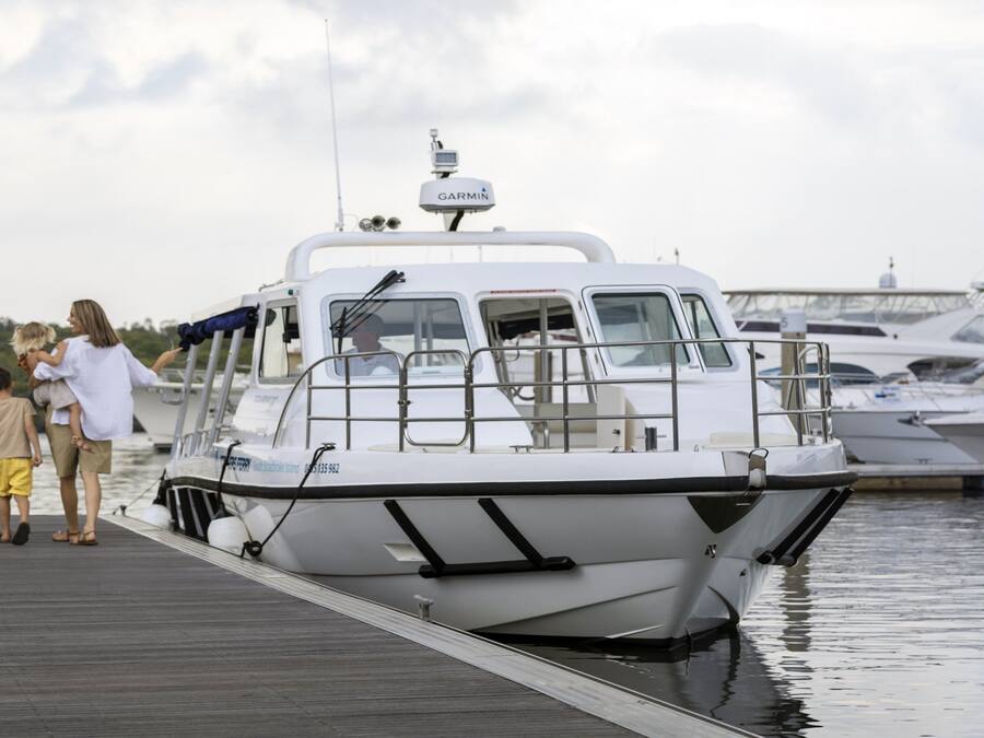 A family boarding a white boat with a Garmin device on top, docked at a marina with other boats.
