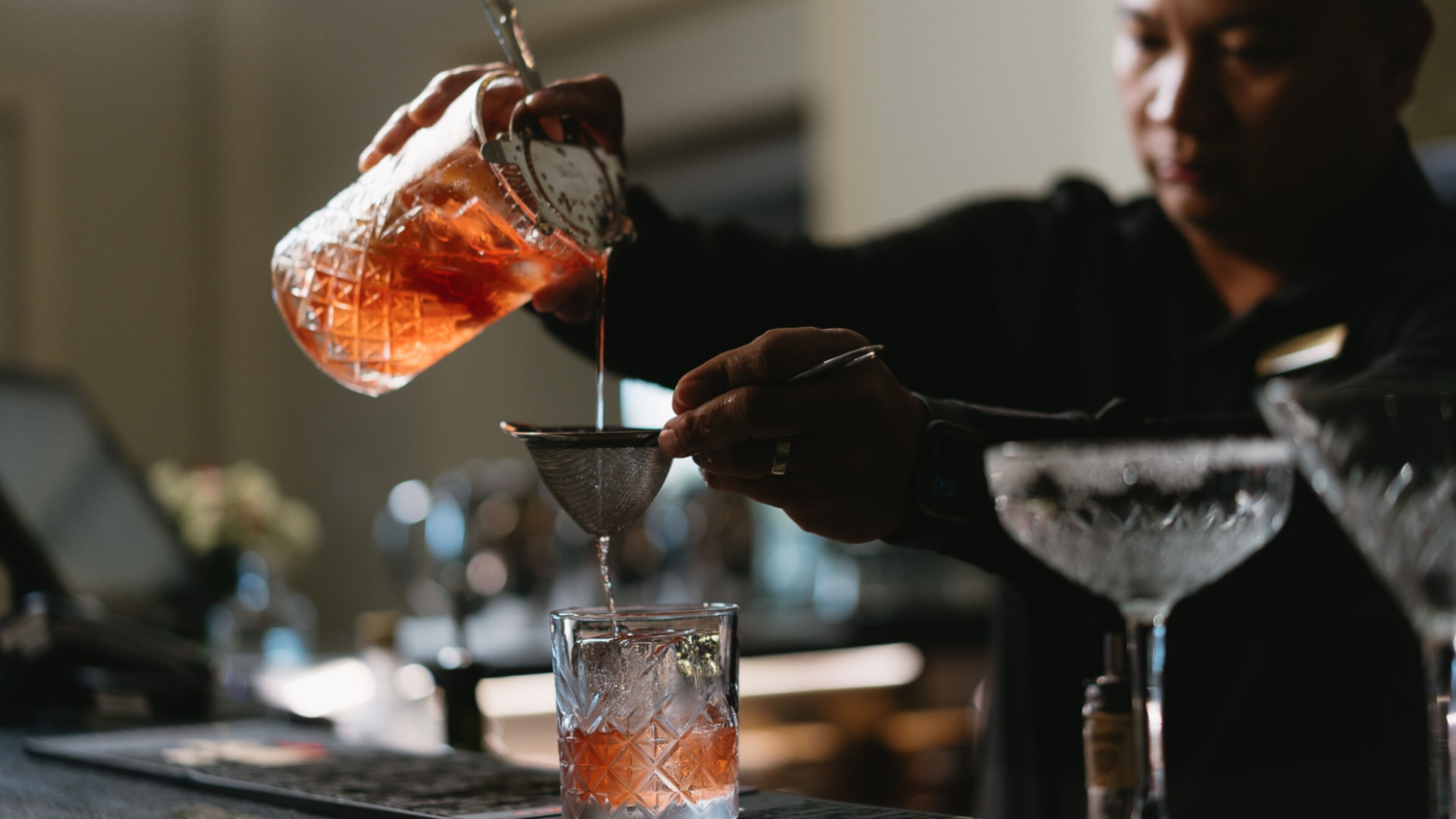 A person pouring a drink into a glass with a unique pattern.