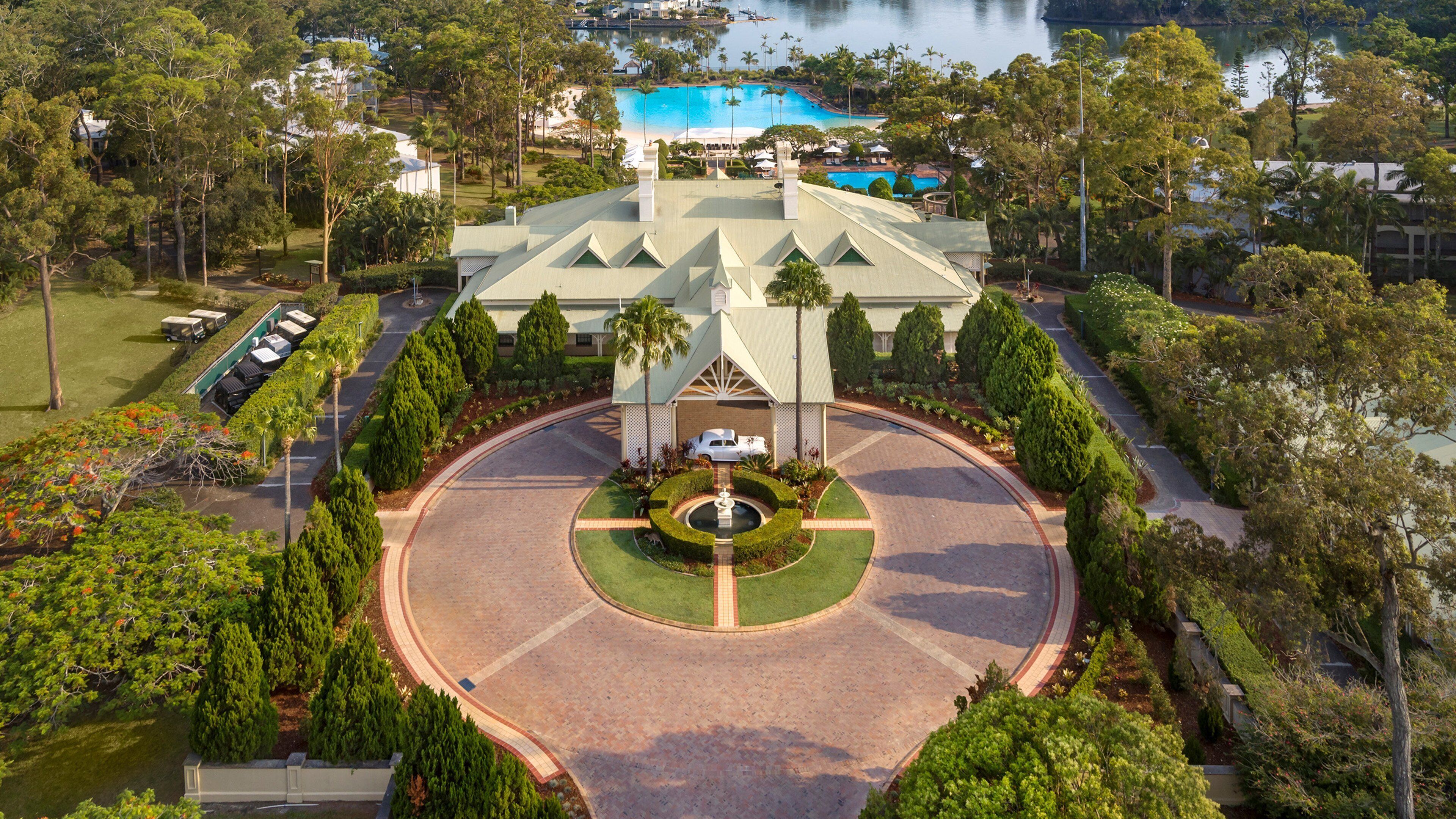 A large building with a central courtyard, surrounded by trees and a pool.