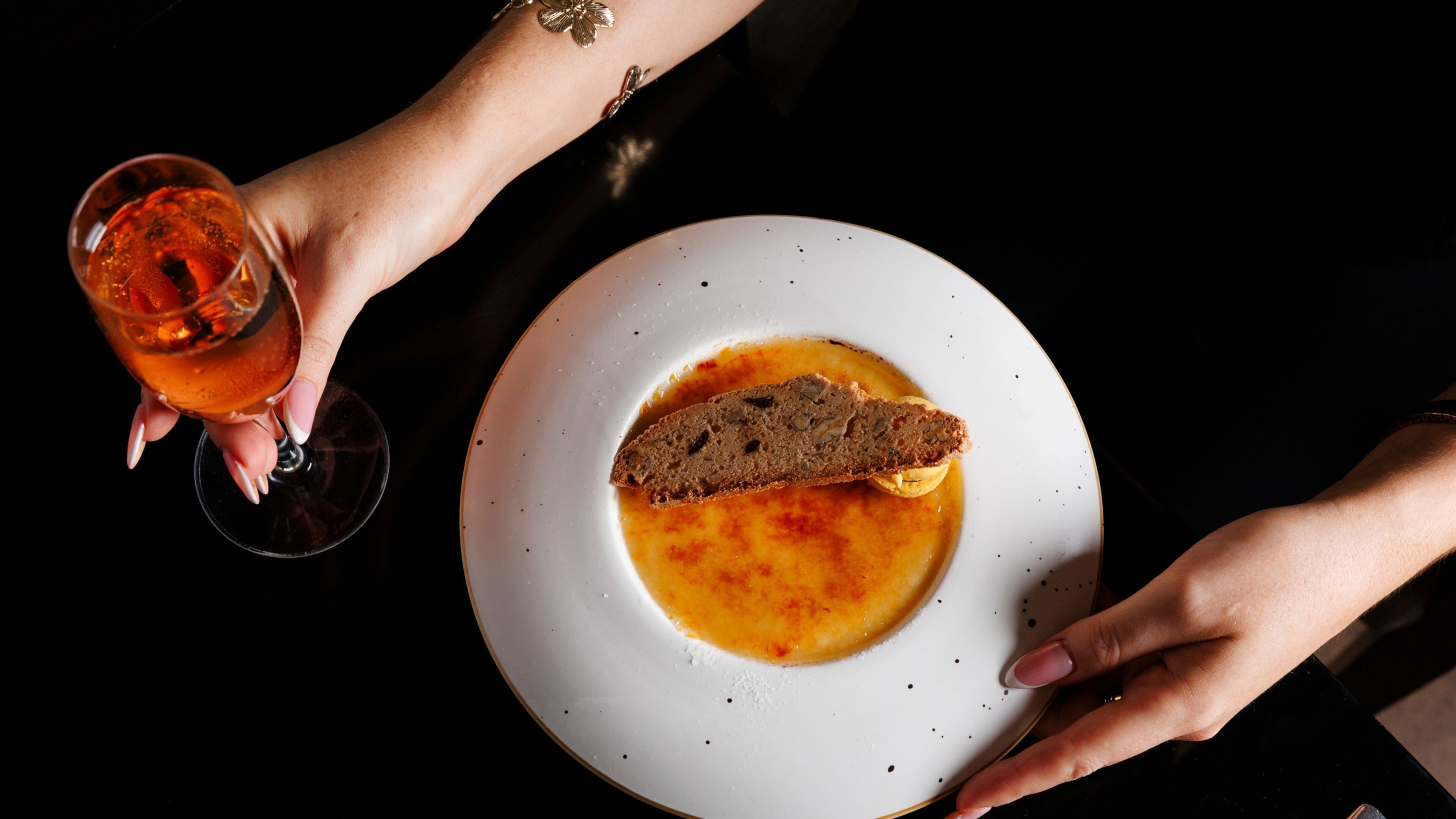 A plate with soup and a slice of bread, and a glass of a beverage.