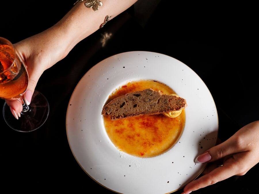 A plate with soup and a slice of bread, and a glass of a beverage.