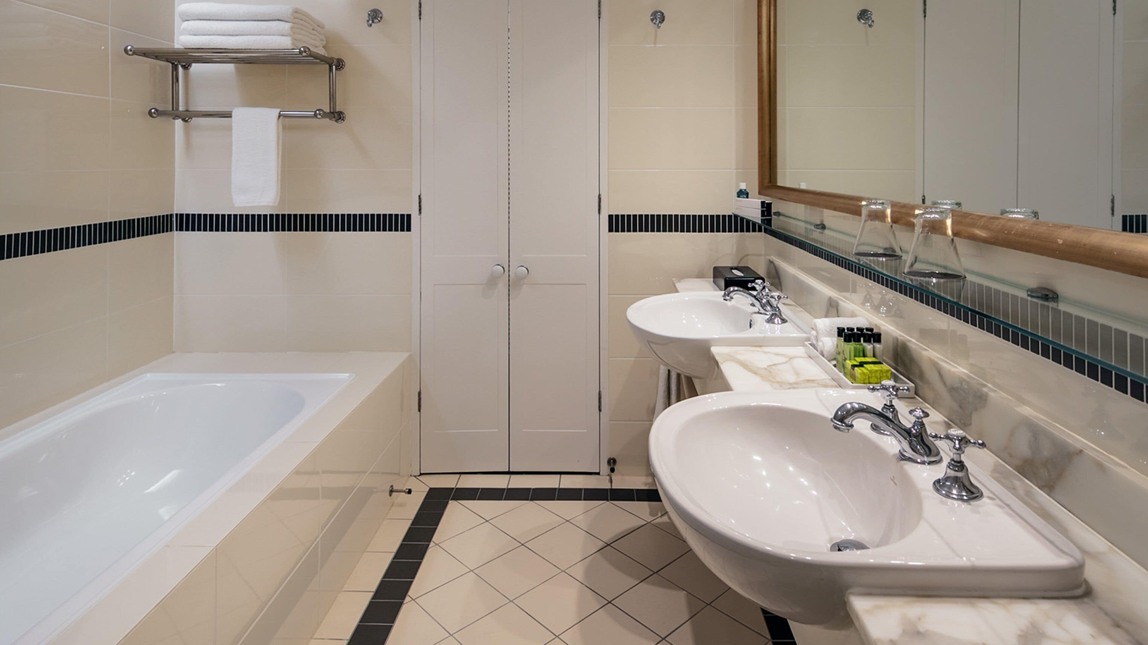 A modern bathroom with a bathtub, two sinks, and a shower stall.