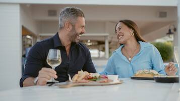 Una mesa de comedor con comida, una copa de vino y un teléfono inteligente.