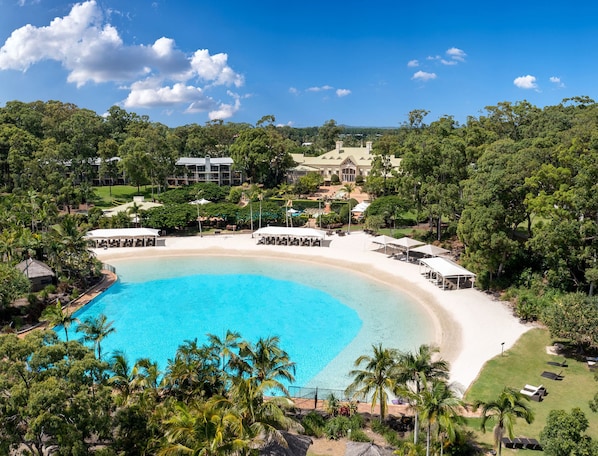 A resort with a large pool, beachfront seating, and lush greenery. - InterContinental Sanctuary Cove Resort by IHG (Hope Island)