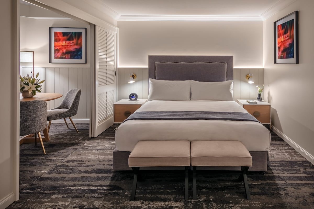 Une chambre moderne avec un grand lit, des tables de chevet, un bureau et des chaises.