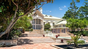 A large, modern building with a central staircase leading to a gated entrance, surrounded by well-maintained gardens and a fountain. - InterContinental Sanctuary Cove Resort by IHG (Hope Island)
