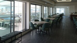 Un moderno salón de conferencias con paredes de vidrio, ventanas amplias y una larga mesa con sillas.