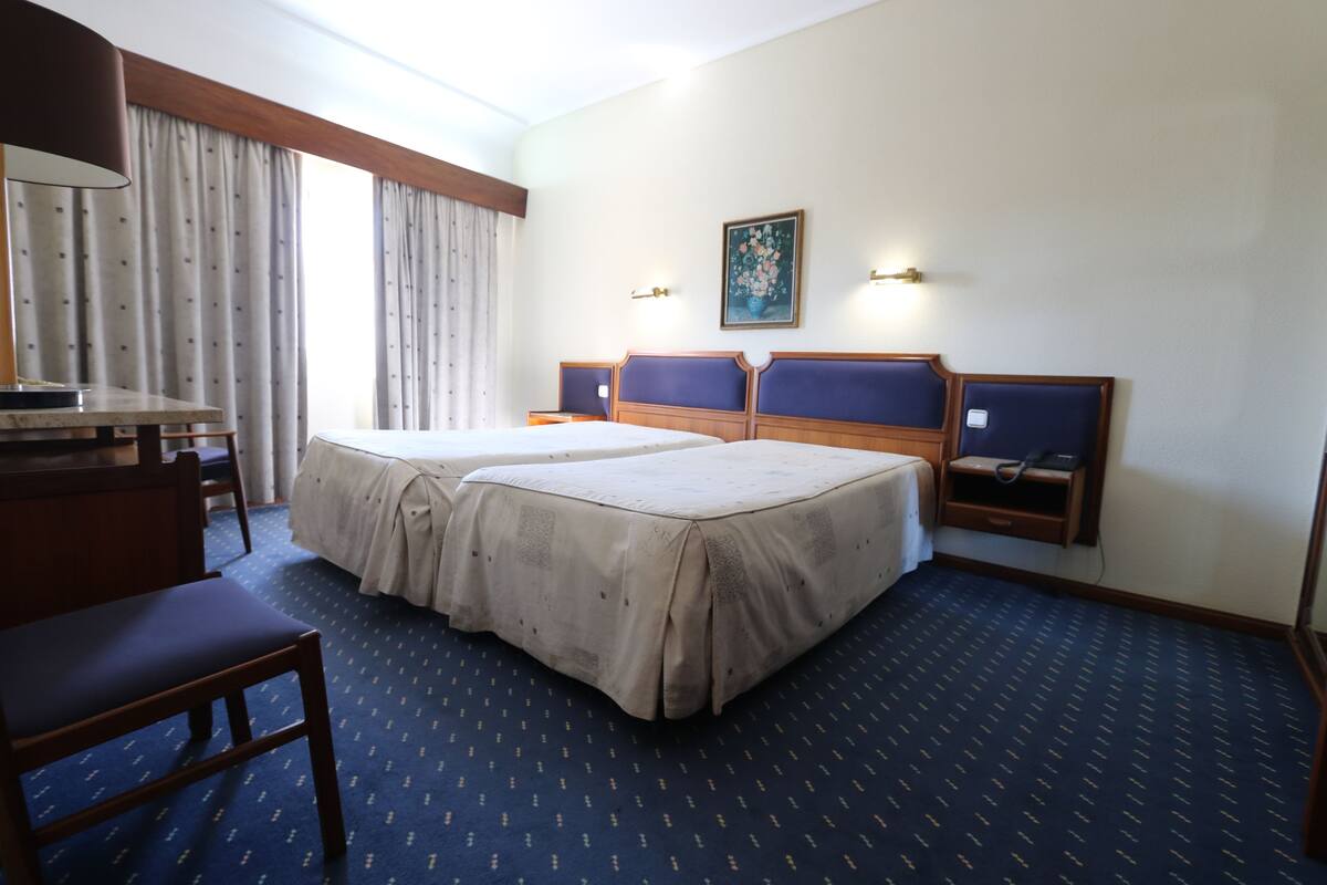 A hotel room with two beds, a desk, and a chair.