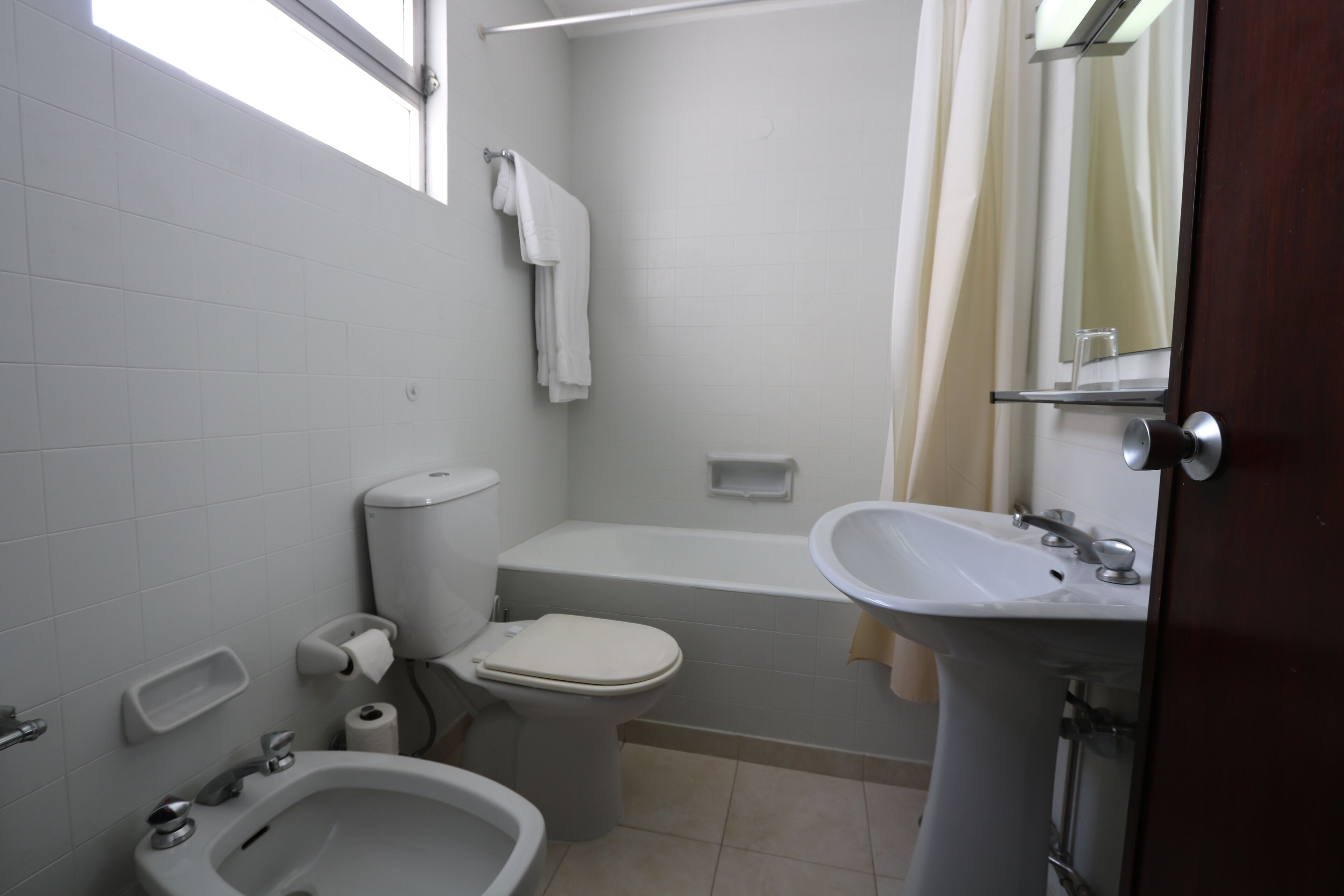 A bathroom with a toilet, bidet, sink, and bathtub.