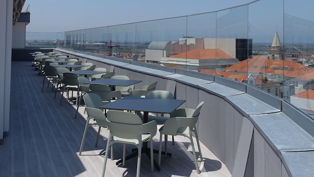 Una terraza en la azotea con mesas y sillas, que ofrece vistas de la ciudad.