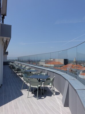 A rooftop terrace with tables and chairs, offering a view of the cityscape. - Hotel Imperial (Aveiro)