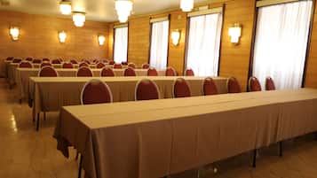 Un salón de conferencias con varias mesas y sillas, dispuestas en filas.
