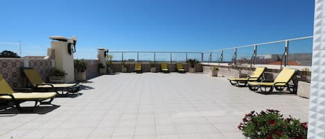 Una terraza en la azotea con tumbonas y plantas en macetas.