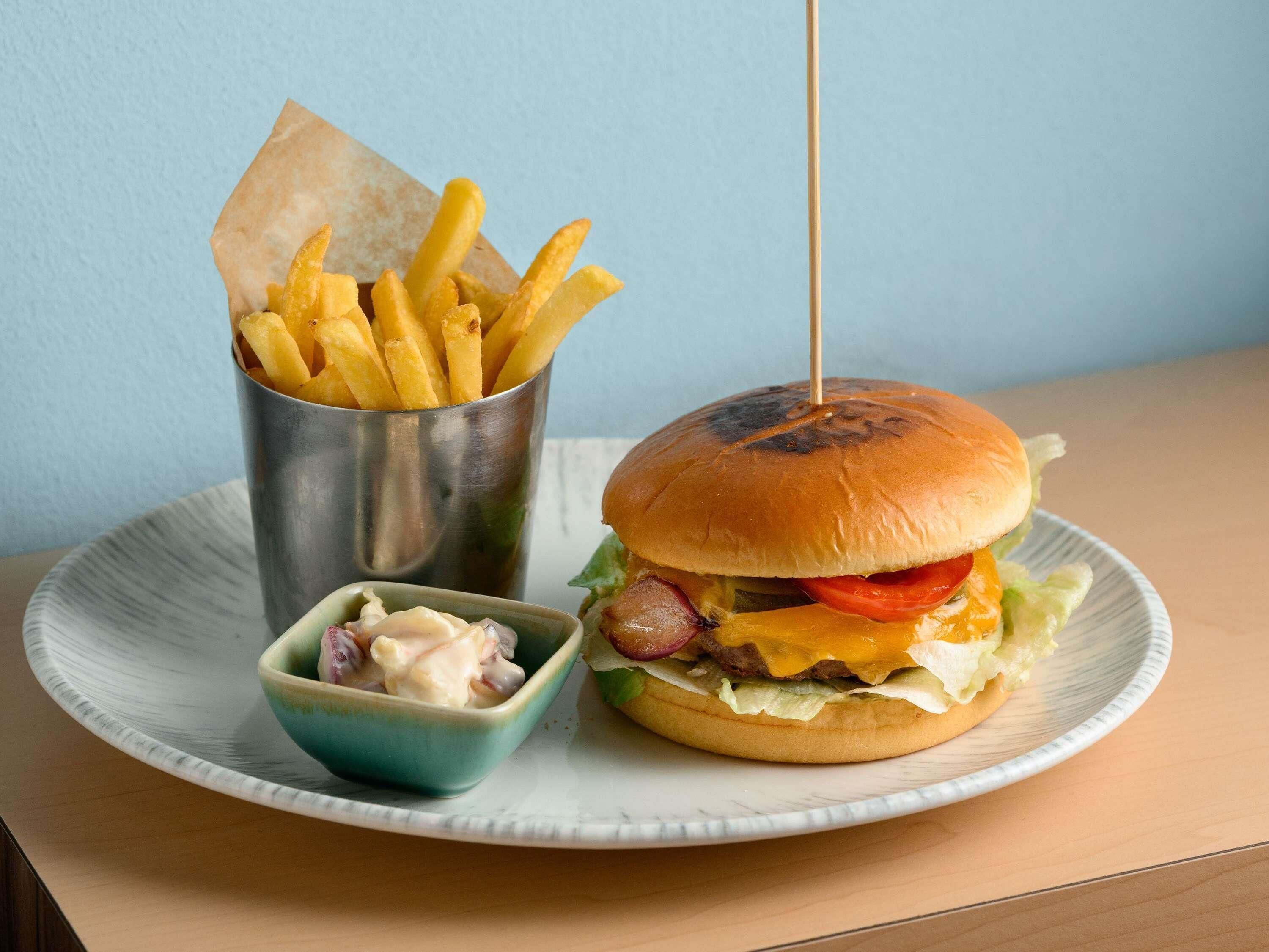 Een bord met een hamburger, frieten en een klein bakje saus.