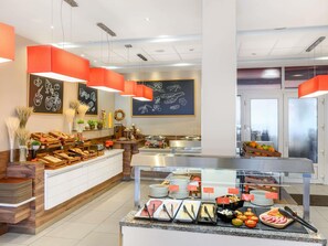 A buffet area with various food items, a chalkboard menu, and a modern interior design. - ibis Budapest Citysouth (Budapest)