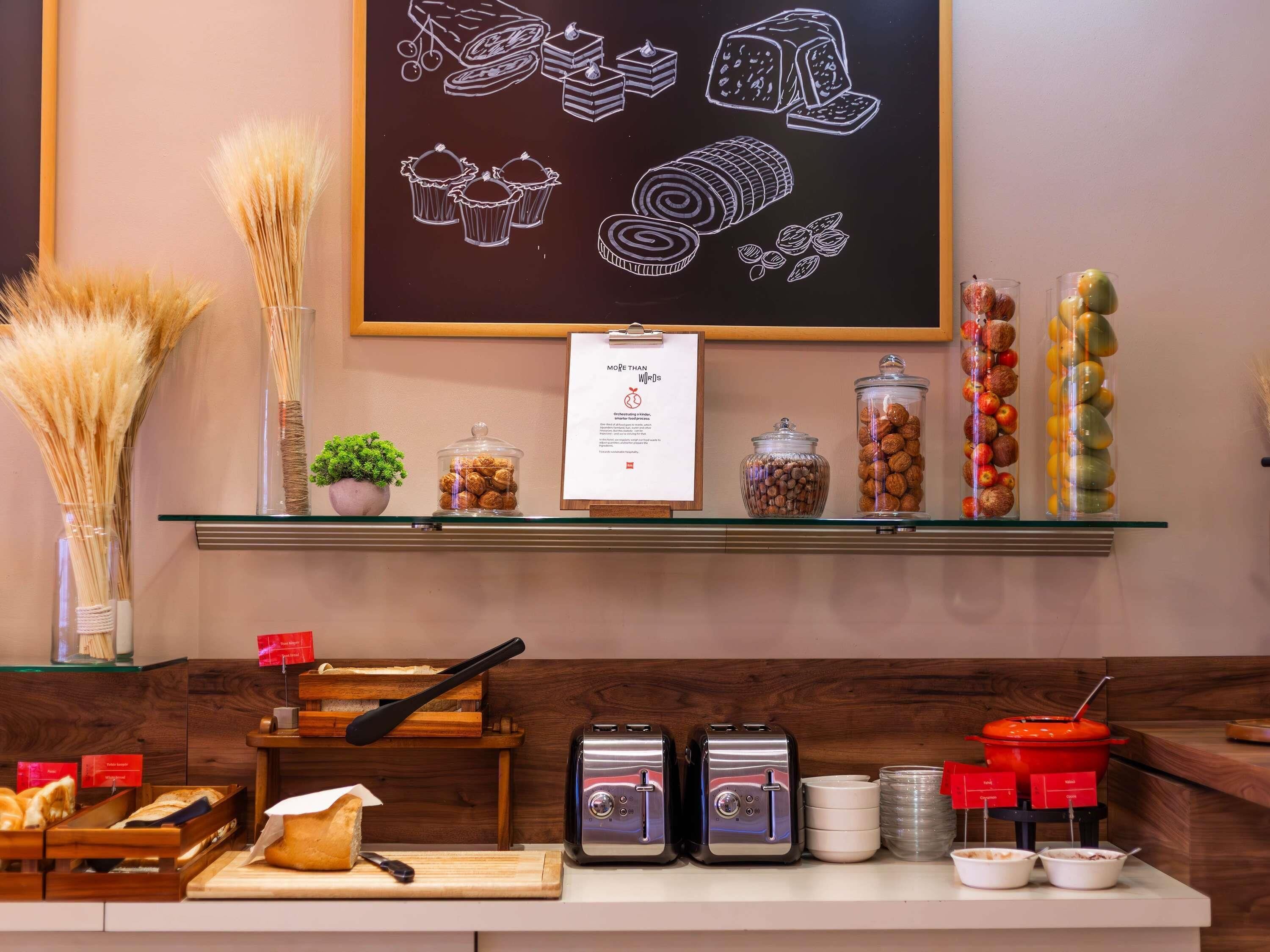 A breakfast buffet area with various food items, a chalkboard with food illustrations, and a sign detailing the menu.