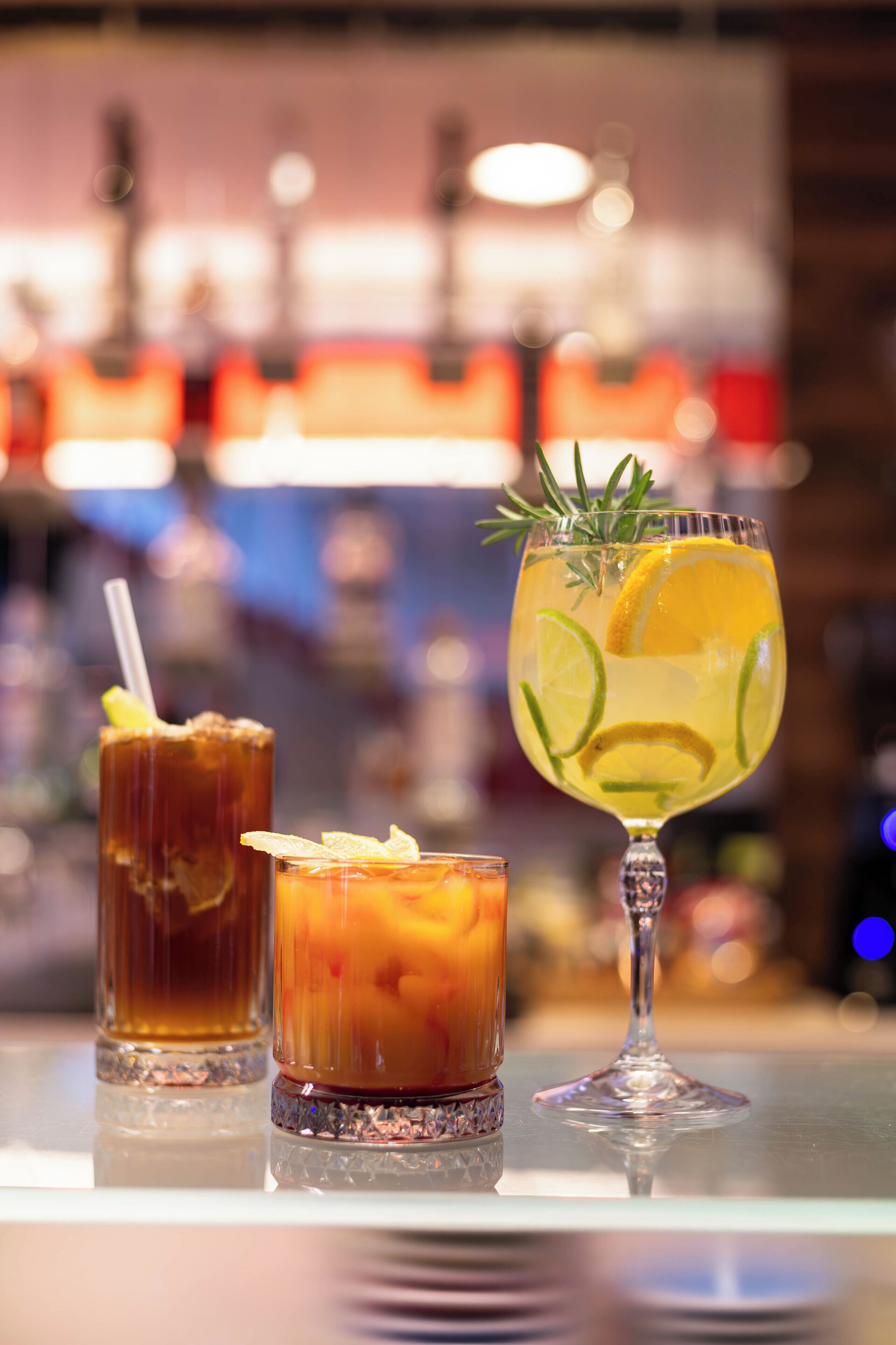 Three glasses of beverages on a bar counter.
