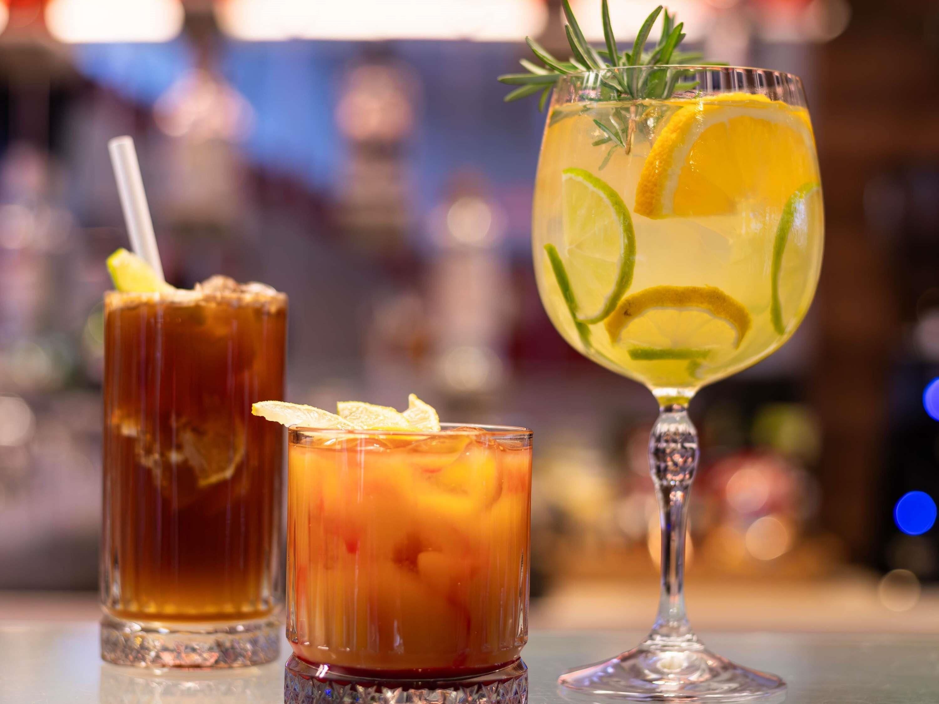 Tres vasos de bebidas sobre una barra.