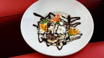 Un dessert servi dans une assiette blanche, nappé de chocolat et décoré de quartiers d’orange.