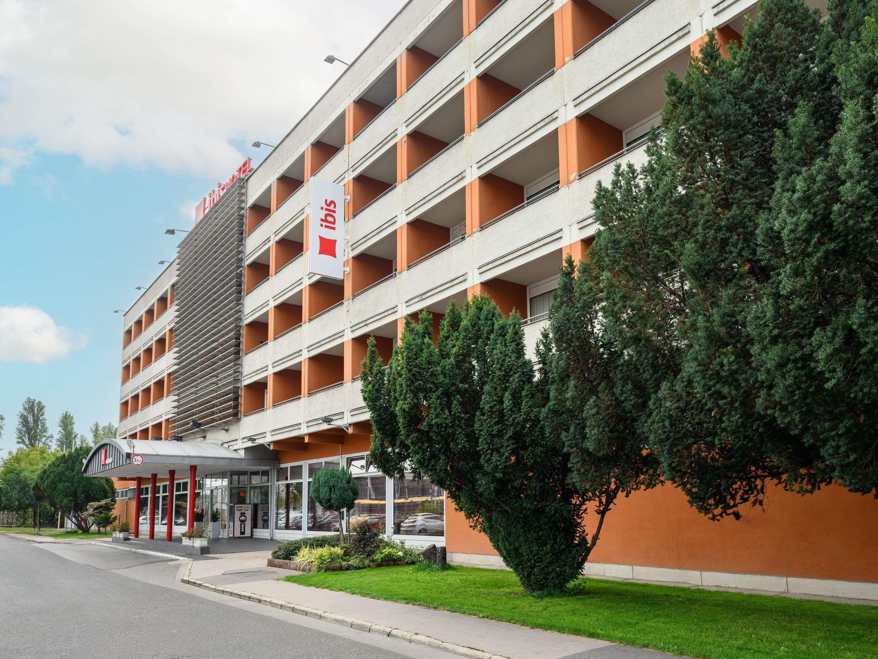 Un estacionamiento de varios pisos con un cartel que indica 'Parking' y un edificio de fachada de vidrio.