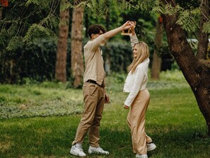 Una pareja tomándose de las manos bajo un árbol en un espacio cubierto de césped.