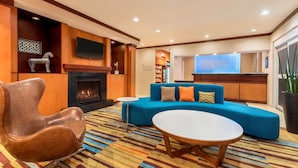 A modern living room with a fireplace, a blue sofa, a brown leather chair, and a small white table.