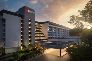 Un hotel Marriott con diseño moderno, que cuenta con una entrada destacada y una zona de estar exterior cubierta.