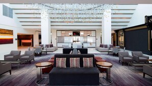 A spacious lobby with a central seating area, a reception desk, and a large screen. - Hanover Marriott (Whippany)